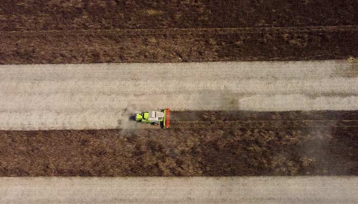 Horizontal Drone Shot Of A Combine Harvester Harvesting Feed Beans